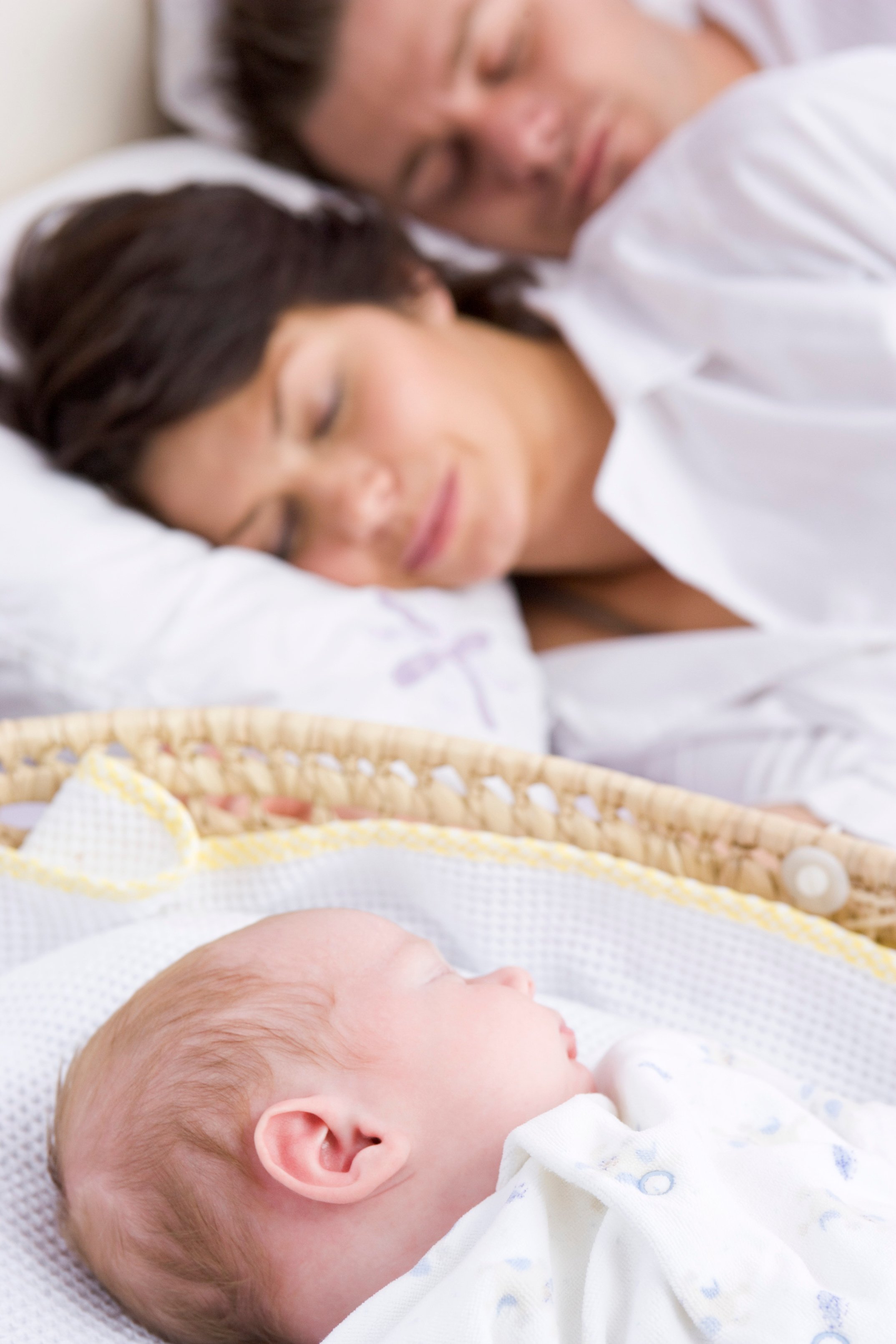 Baby sleeping in bassinet by parents' bed