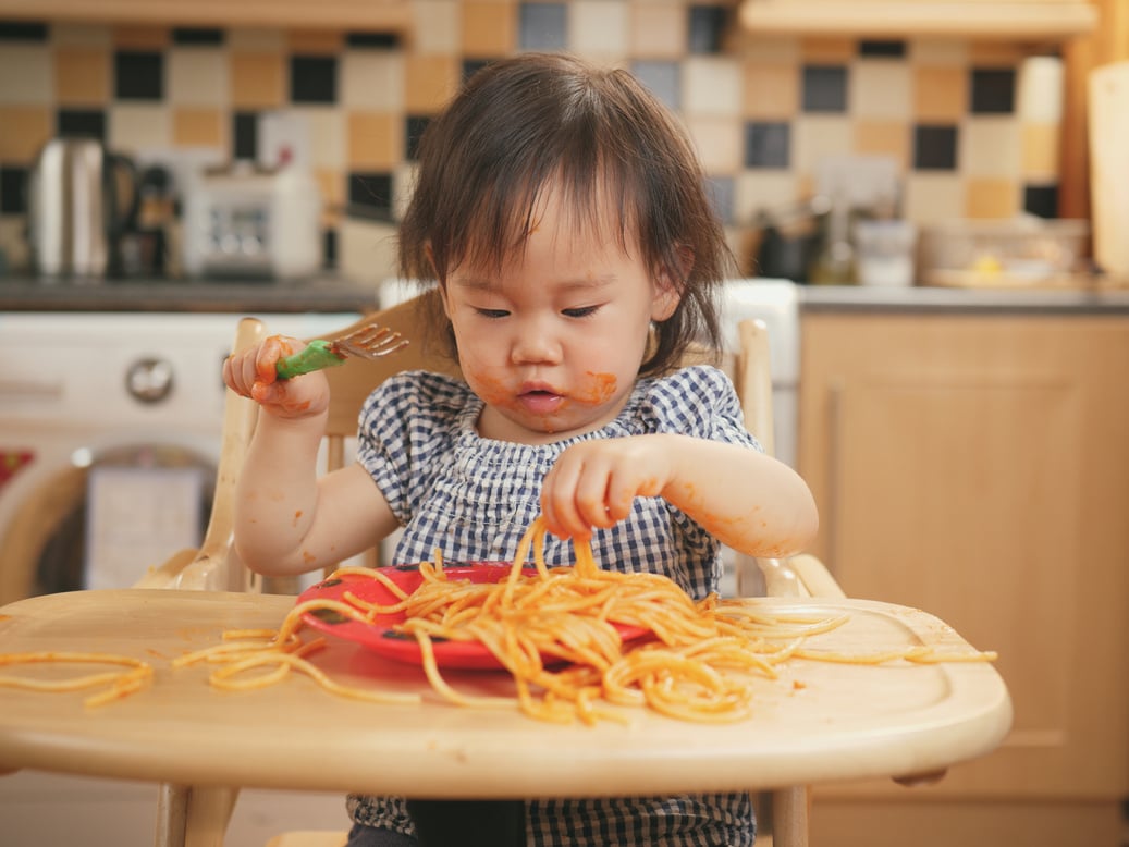 baby girl eating messy spaghetti